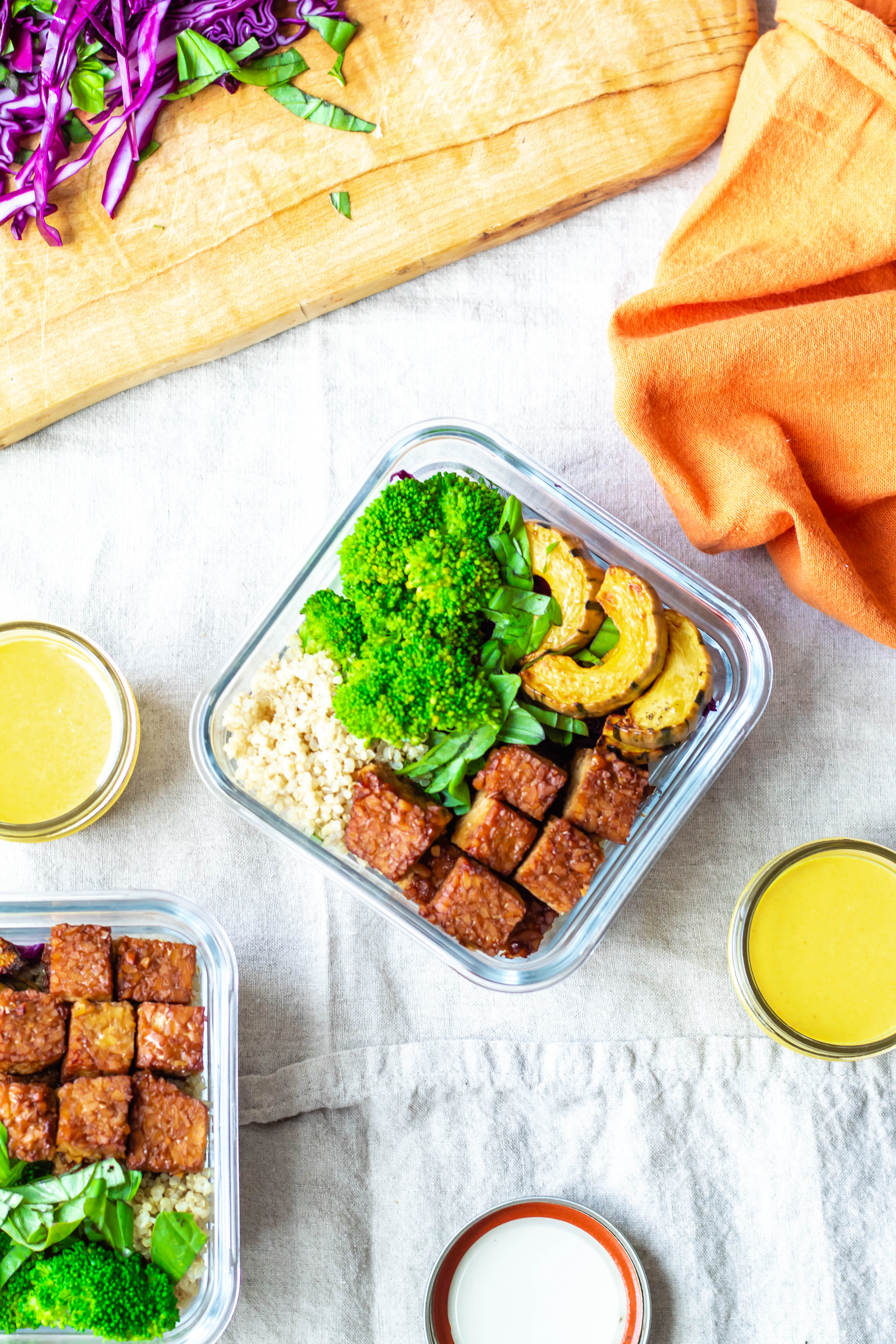 Vegan Lunch Prep Tempeh and Roasted Squash Buddha Bowls Recipe (an overhead photo of all of the components in a container with turmeric tahini sauce on the side)