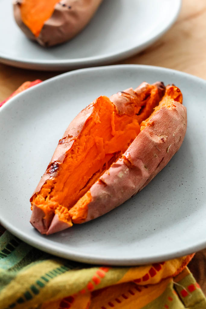 a baked sweet potato sliced in half on a blue plate 