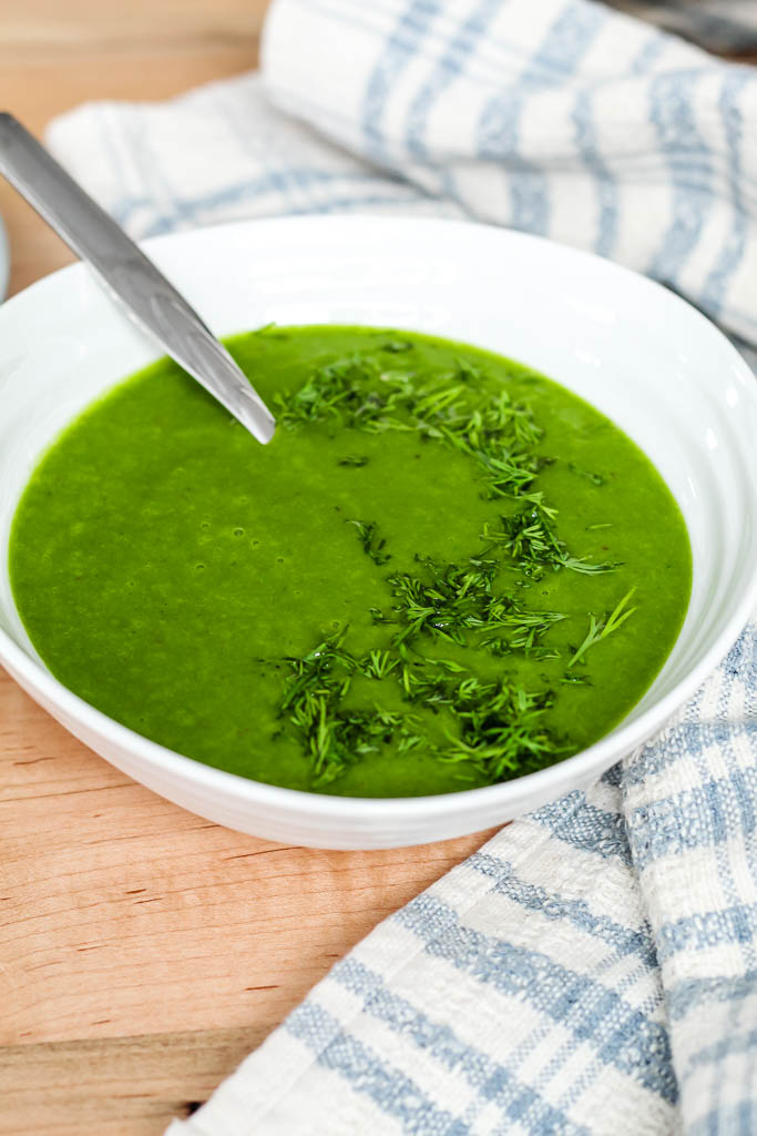 the vegan spinach potato soup in a white bowl with fresh dill on top. 