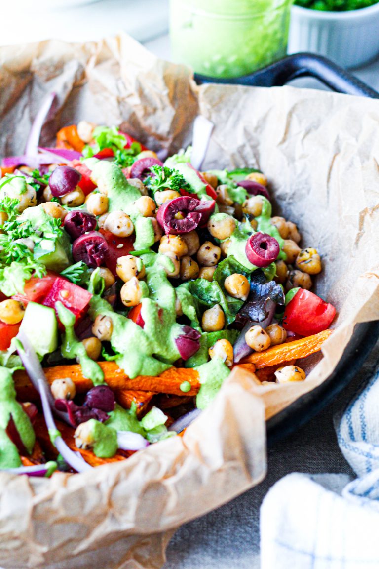 a straight on shot of the loaded mediterranean vegan fries, showing the lemon herb tahini sauce atop each and every bite