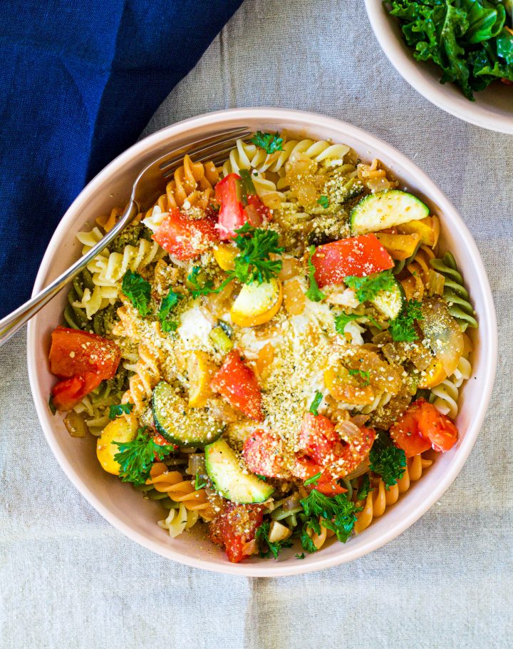 overhead shot of a bowl of the lemon ricotta pasta on tricoloured pasta noodles topped with tomatoes and zucchini