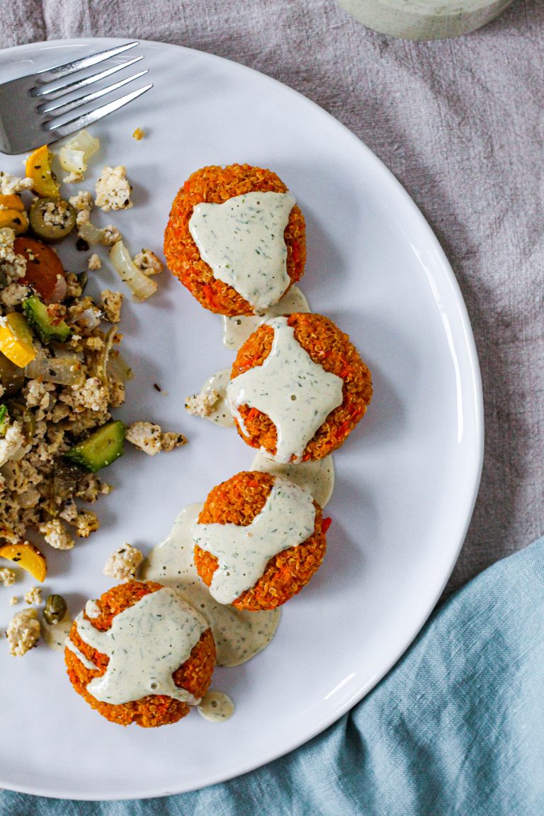 overhead shot of sweet potato quinoa cakes with lemon dill tahini sauce on a white plate