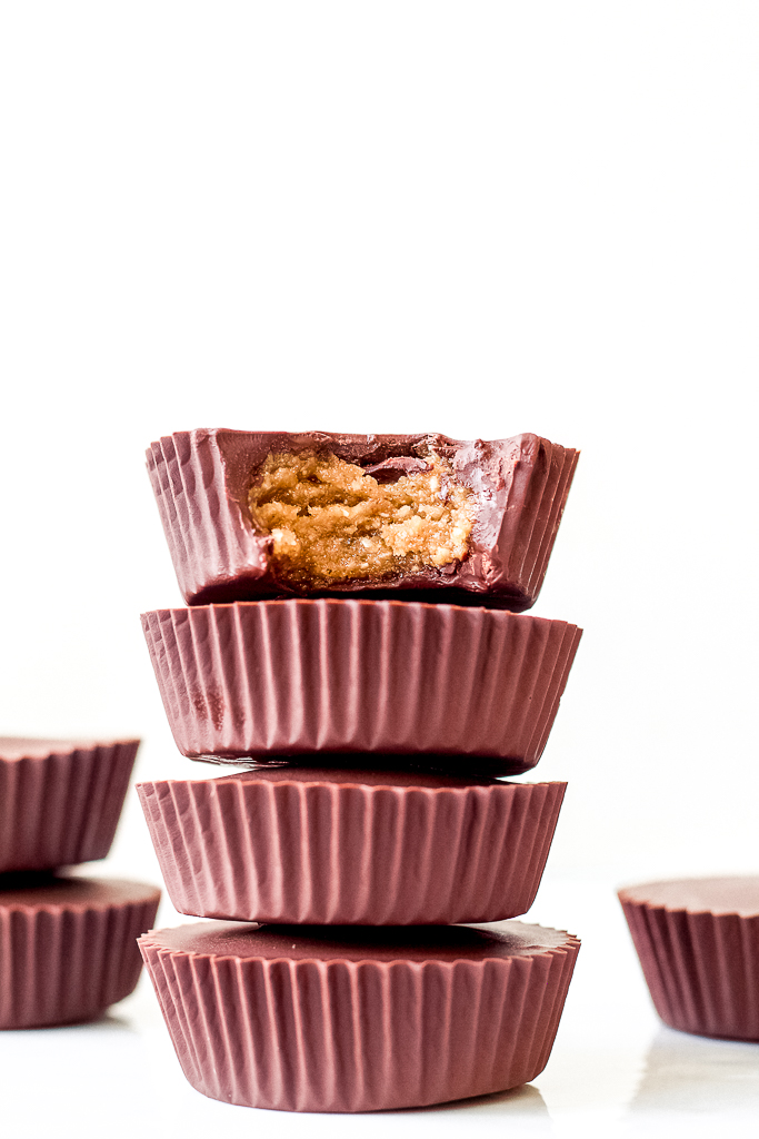 a straight on shot of a stack of four chocolate hazelnut butter cups against a white backdrop