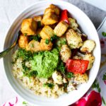 an overhead photo of a bowl of crispy tofu, pesto, roasted vegetables, and quinoa