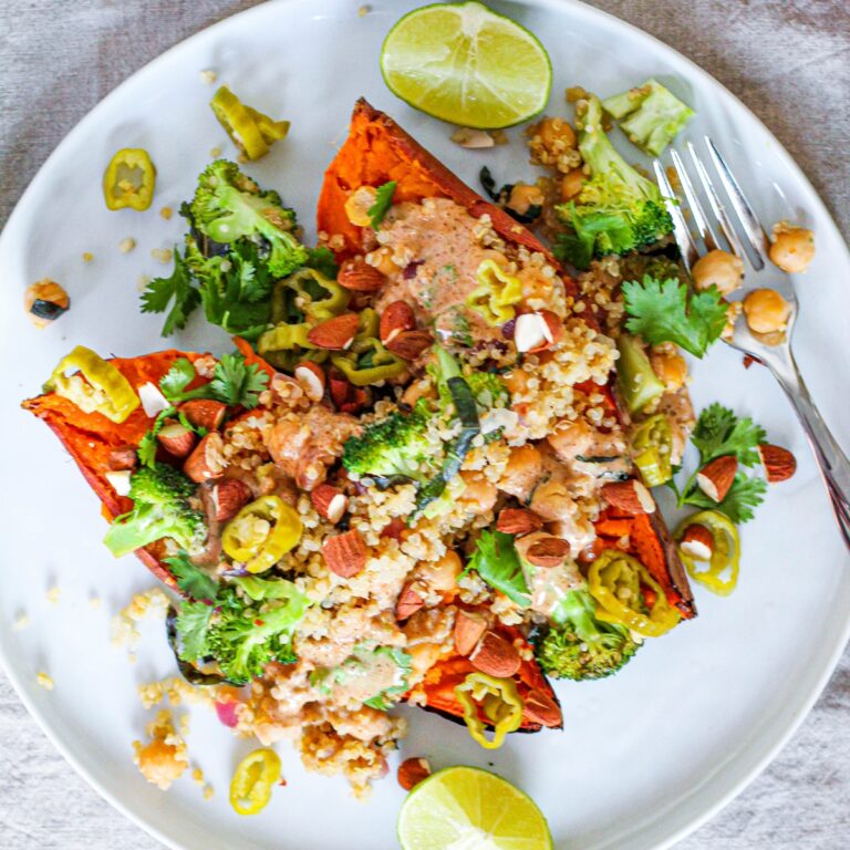 overhead photo of a baked sweet potato sliced in half and topped with the Thai quinoa and chickpea filling and almond butter sauce