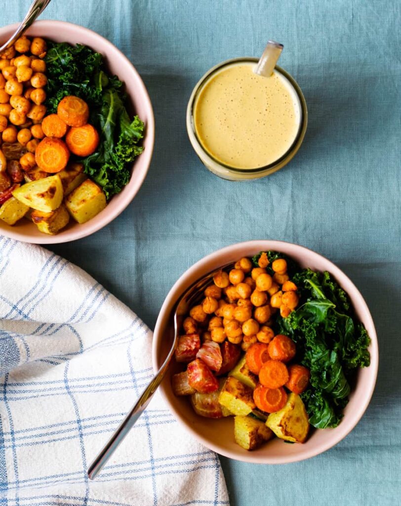 overhead shot of two of the roasted root and chickpea bowls and a container of the dressing 