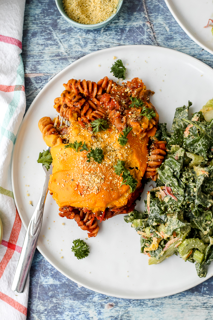 an overhead shot of the lentil mushroom pasta bake on a plate with a side of kale Caesar salad