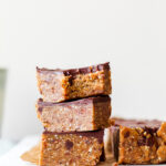 a straight on shot of three cashew cookie dough bars with a bite taken out of the top one