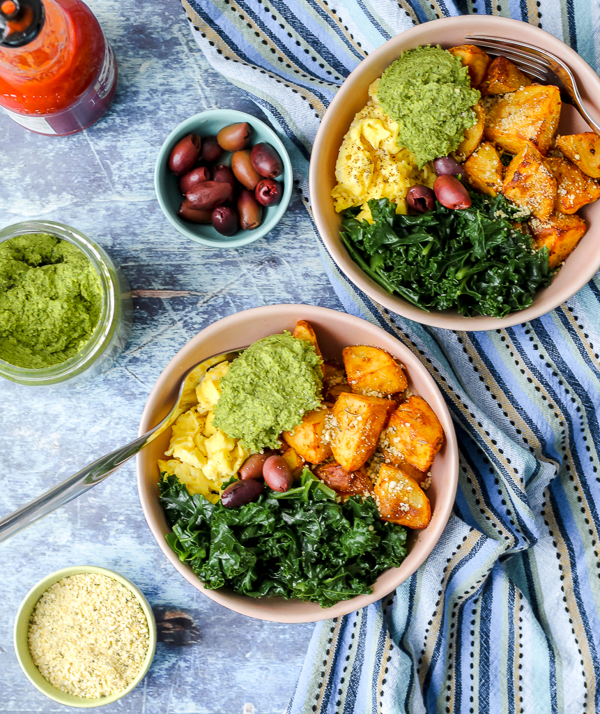 overhead shot of the scrambled egg pesto broccoli bowls on a blue backdrop 