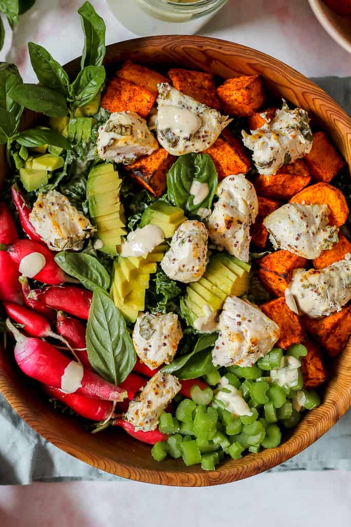 overhead shot of the tahini kale Caesar salad in a big wooden bowl with avocado, sweet potato, and chicken on top