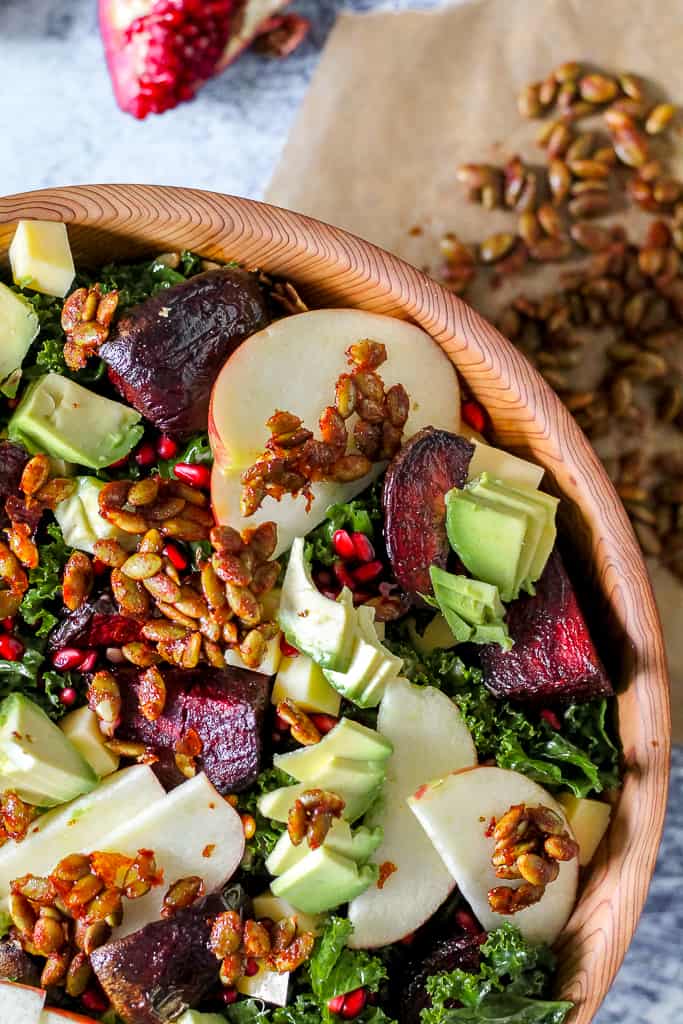 overhead close up of a corner of the salad bowl containing kale, apple, roasted beets, avocado, and pomegranate