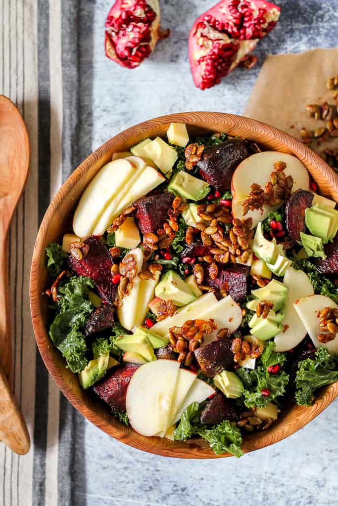 overhead photo of a big wooden bowl of fall harvest roasted beet, avocado, and pomegranate salad