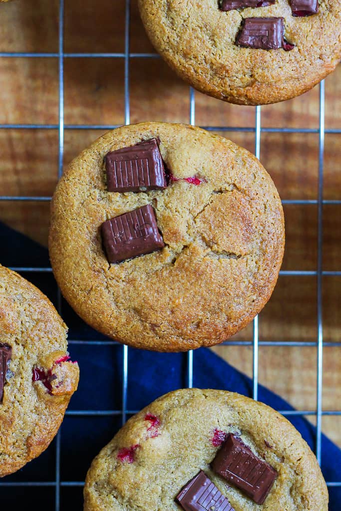 an overhead photo of the healthy orange cranberry chocolate chunk muffins on a wire rack set on a wooden board