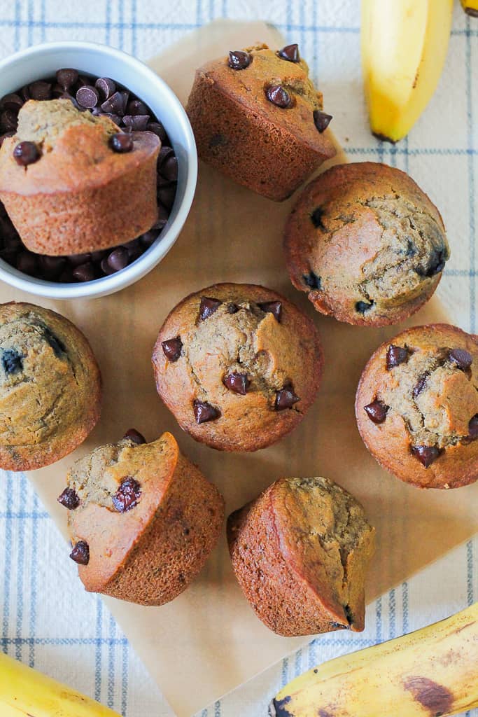 overhead shot of several muffins on a sheet of parchment paper on a checkered blue and white towel