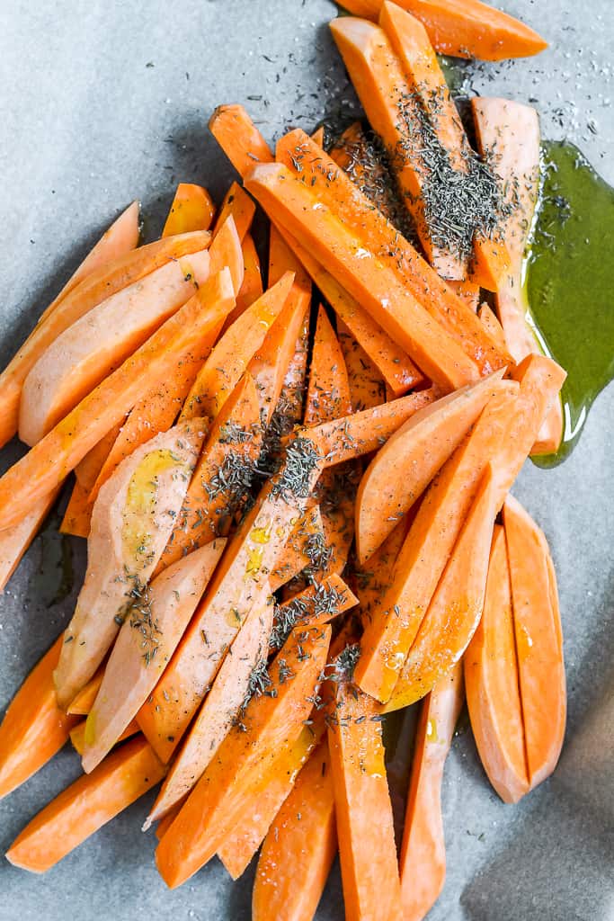 an overhead shot of the sweet potato on a baking sheet before being tossed with oil and herbs