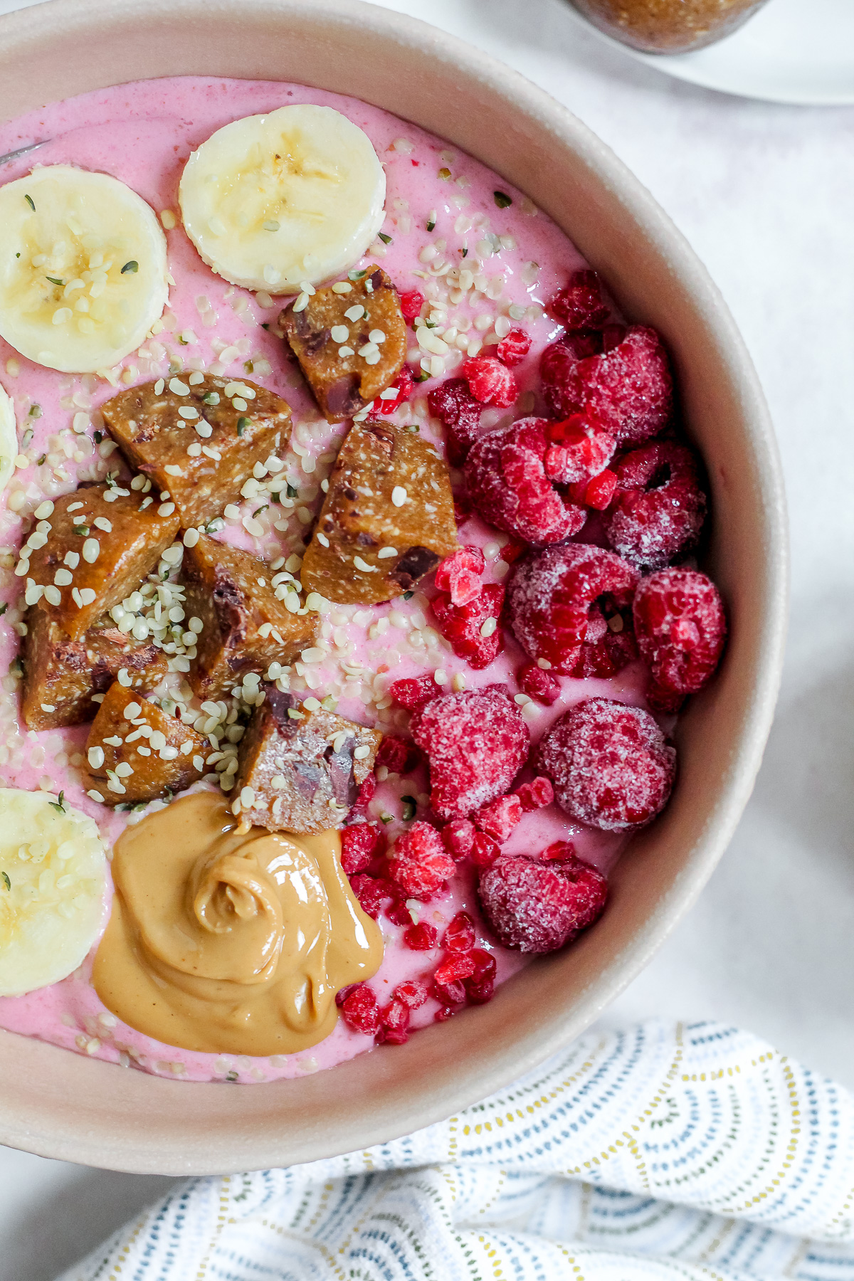 close up overhead shot of the smoothie bowl with raspberries, banana, cashew butter, and energy ball on top