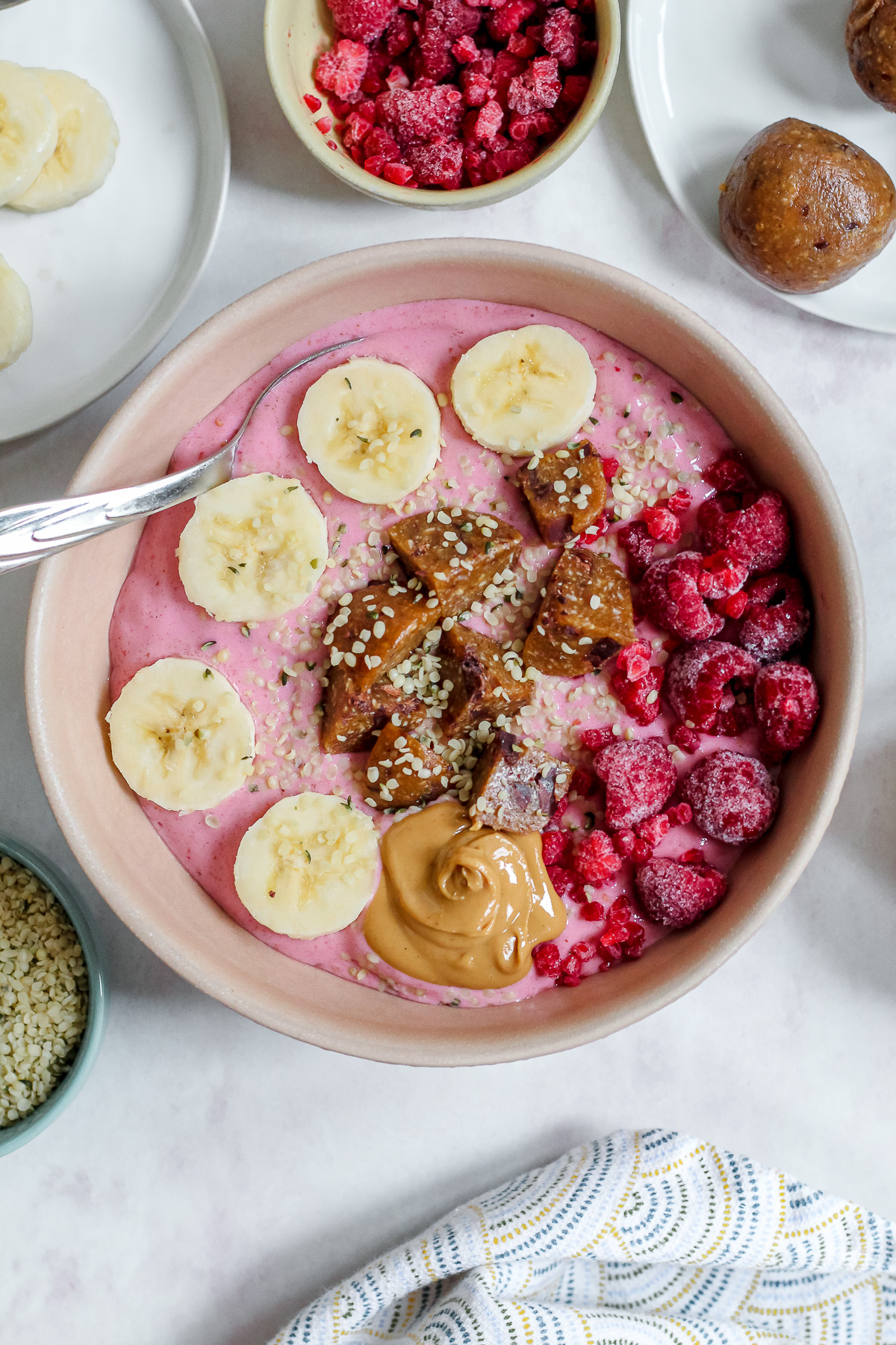 close up overhead shot of the raspberry Greek yogurt smoothie bowl topped with raspberries, banana, cashew butter, and an energy ball