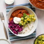 featured image for the post, an overhead shot of the mole chicken, rice, salsa, and cabbage topped with Greek yogurt in a bowl on a light pink backdrop