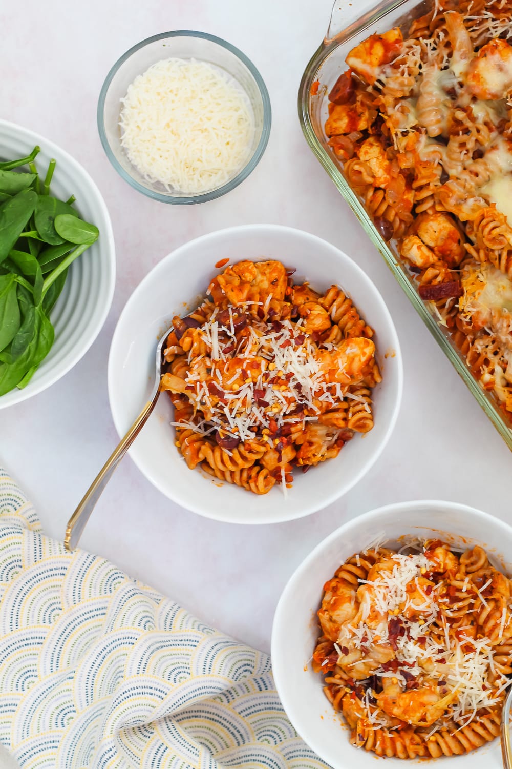 overhead shot of pasta bake in two white bowls on light pink backdrop