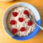 overhead photo of the overnight oats in a bowl topped with raspberries
