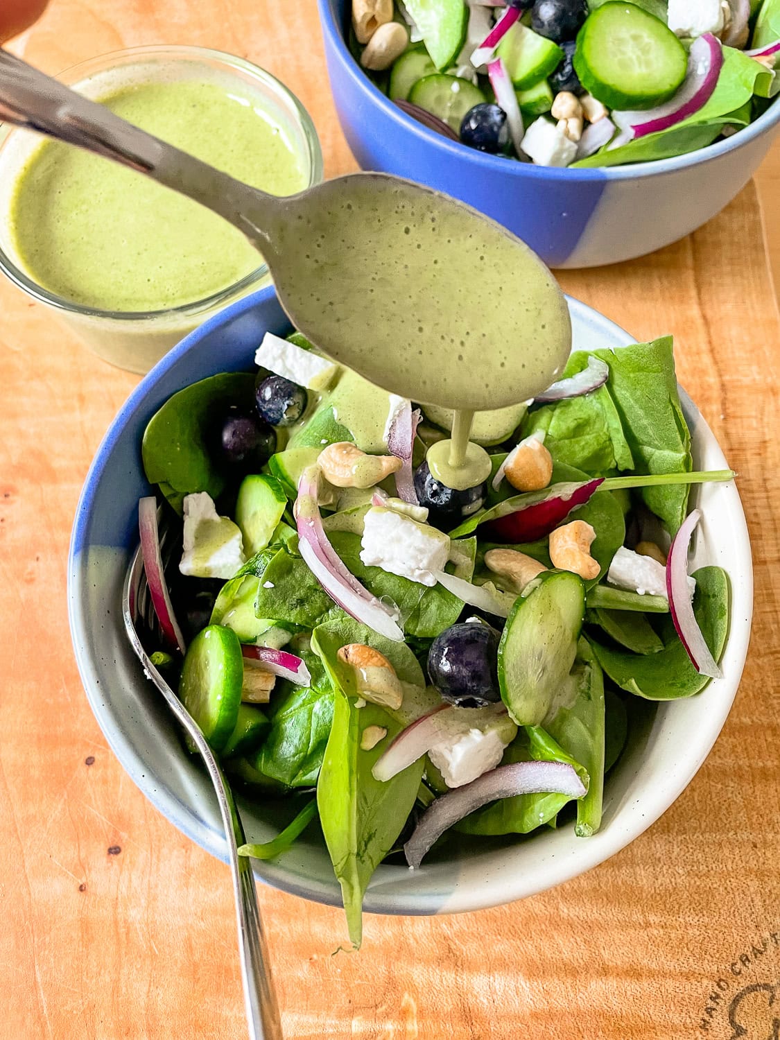 overhead photo of a serving of the salad in a bowl with the lemon mint dressing being spooned over top