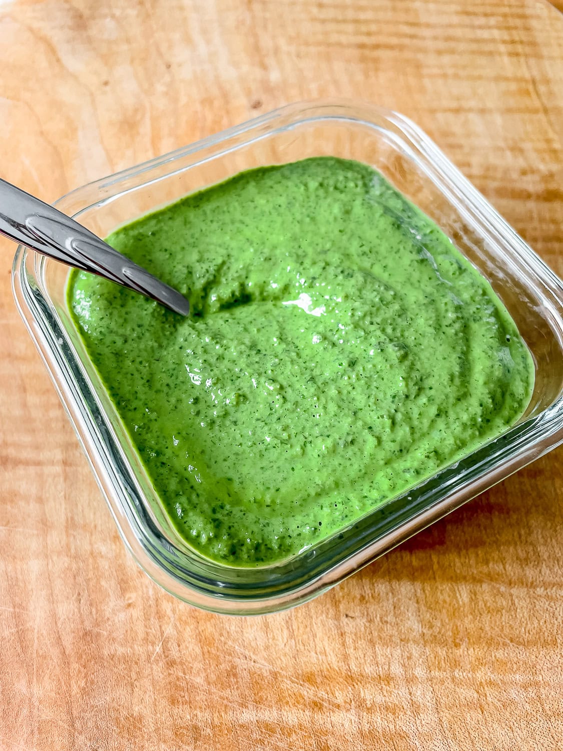 close up photo of the pesto in a container on a wooden board backdrop