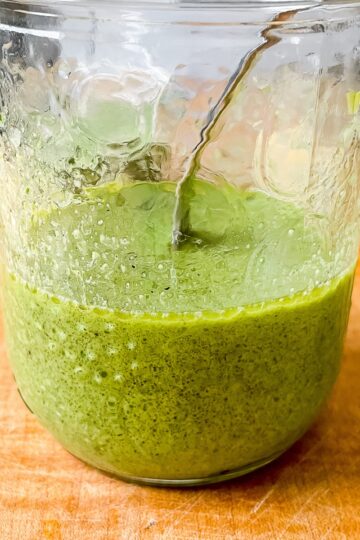 a close up view of the dressing in a glass jar on a wooden board