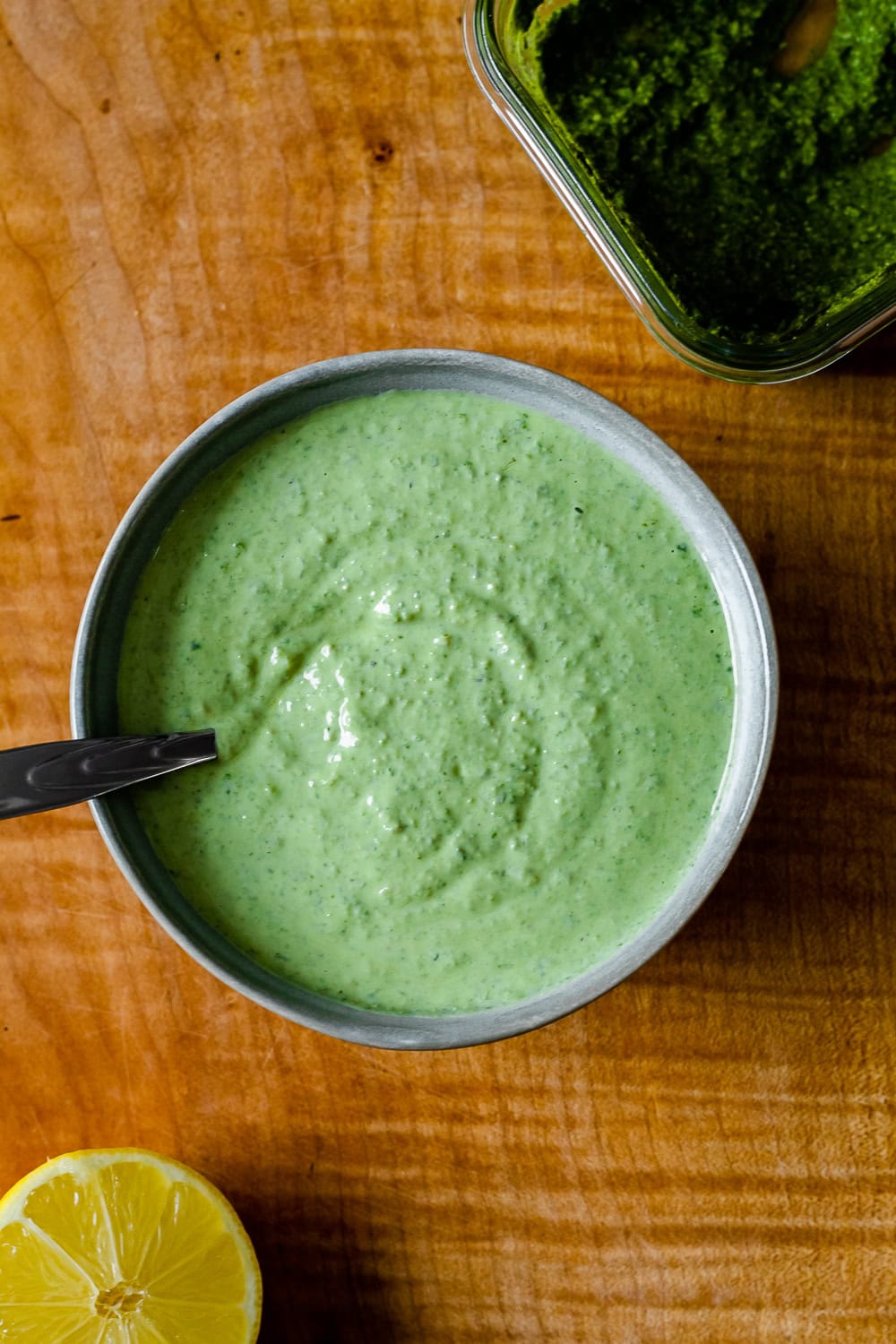 overhead photo of a bowl of the sauce with a container of pesto and a lemon half on either side