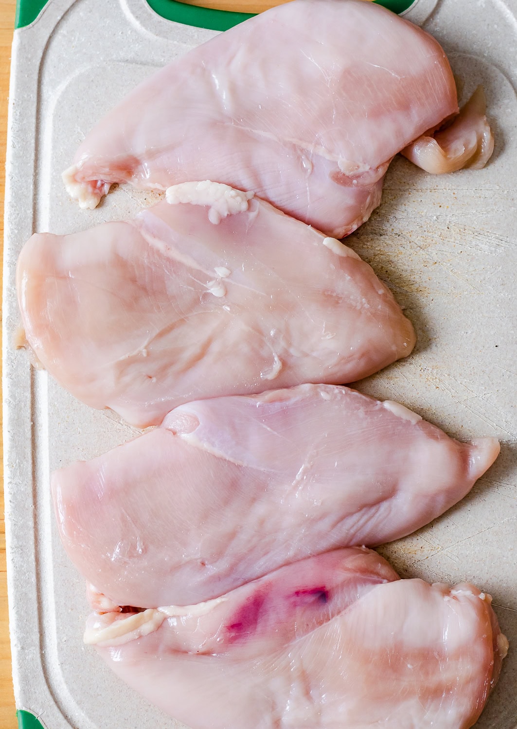 an overhead photo of the tenderized chicken breasts on a cutting board