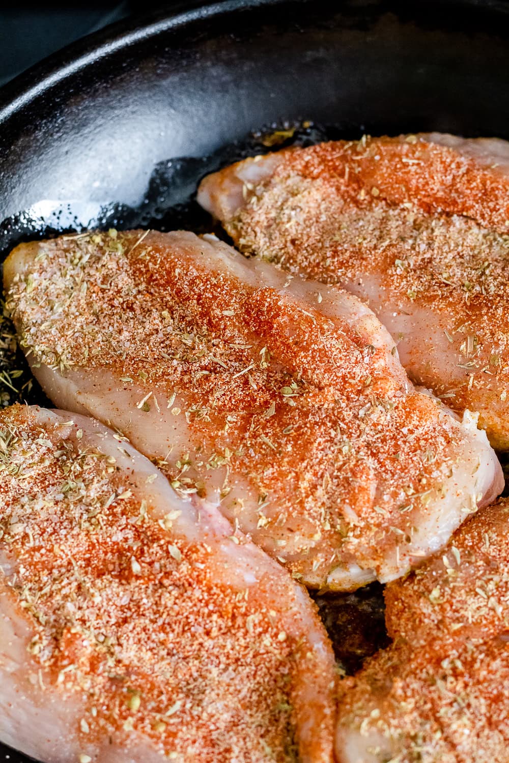 overhead photo of the chicken breasts in the cast iron skillet, being seared before being put into the oven