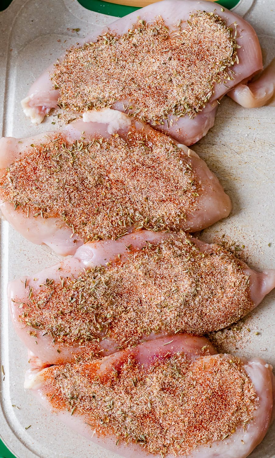 process photo showing the pounded chicken breasts with spice mix on them