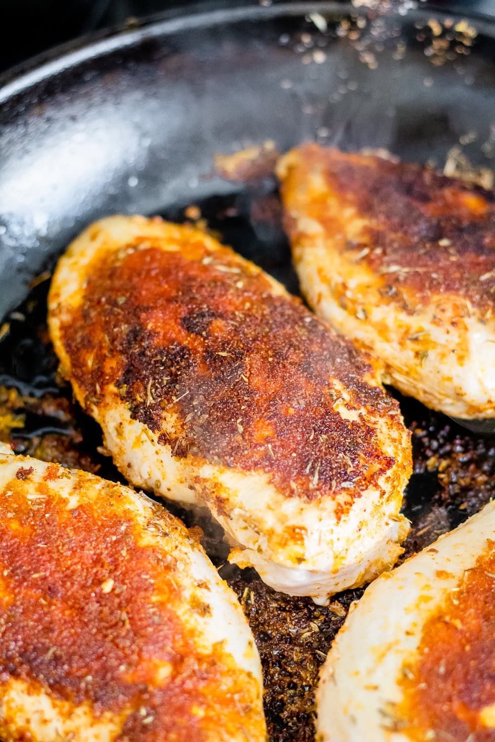 a process photo of the seared chicken breasts right after flipping them in a cast iron skillet
