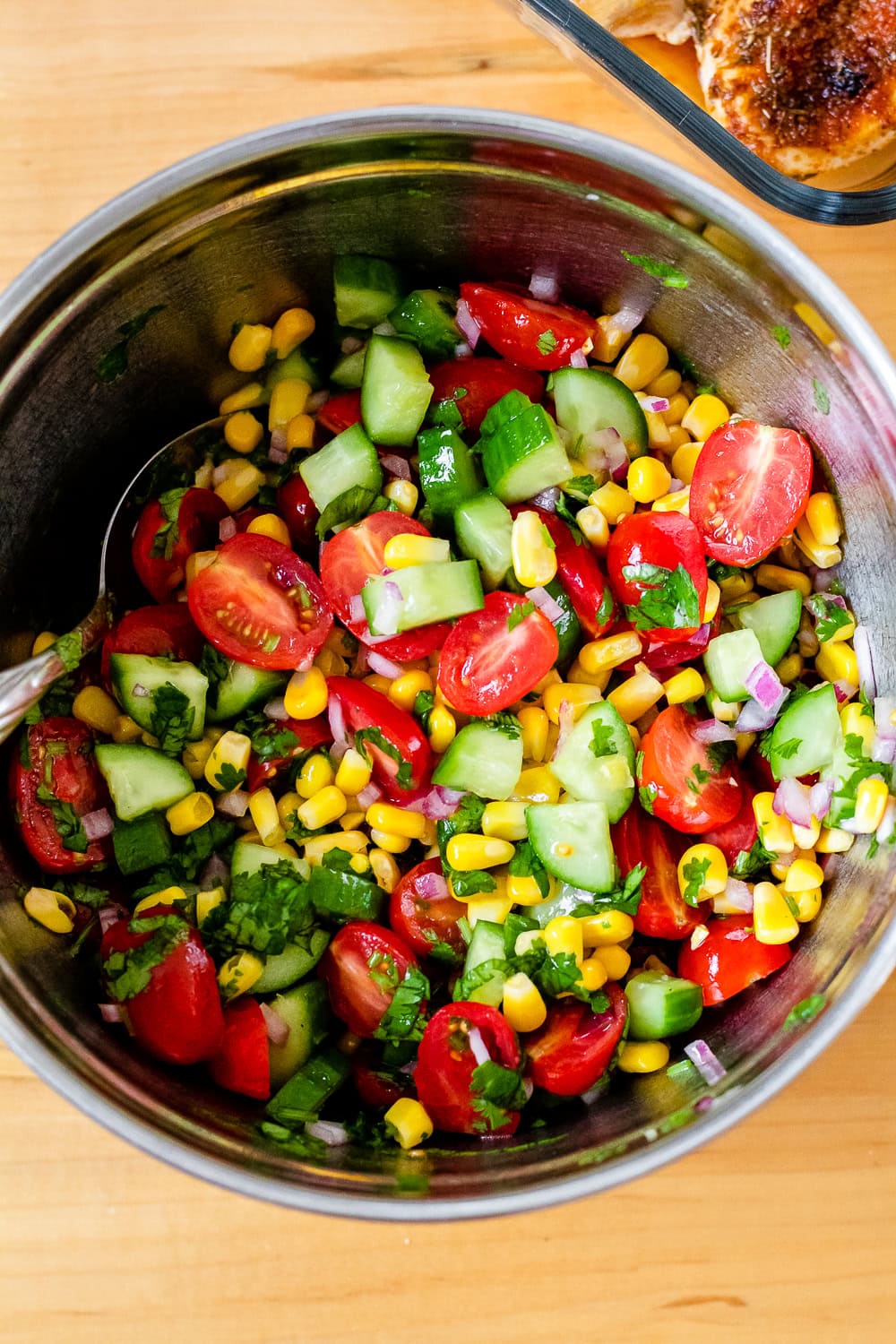 overhead photo of the corn, tomato, and cucumber herb salad in a large mixing bowl