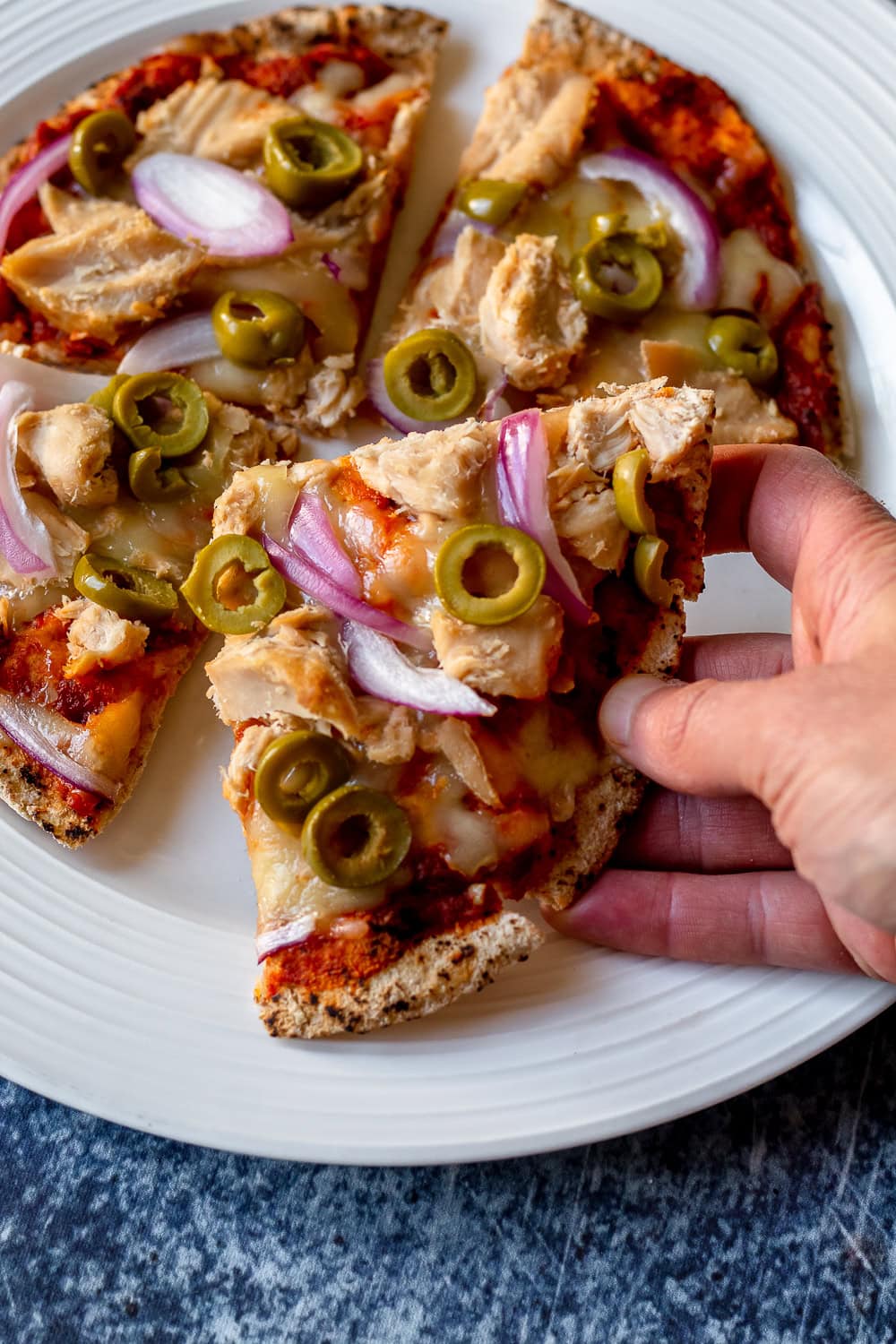 close up of a slice of pizza with tuna, olives, cheese, and onion