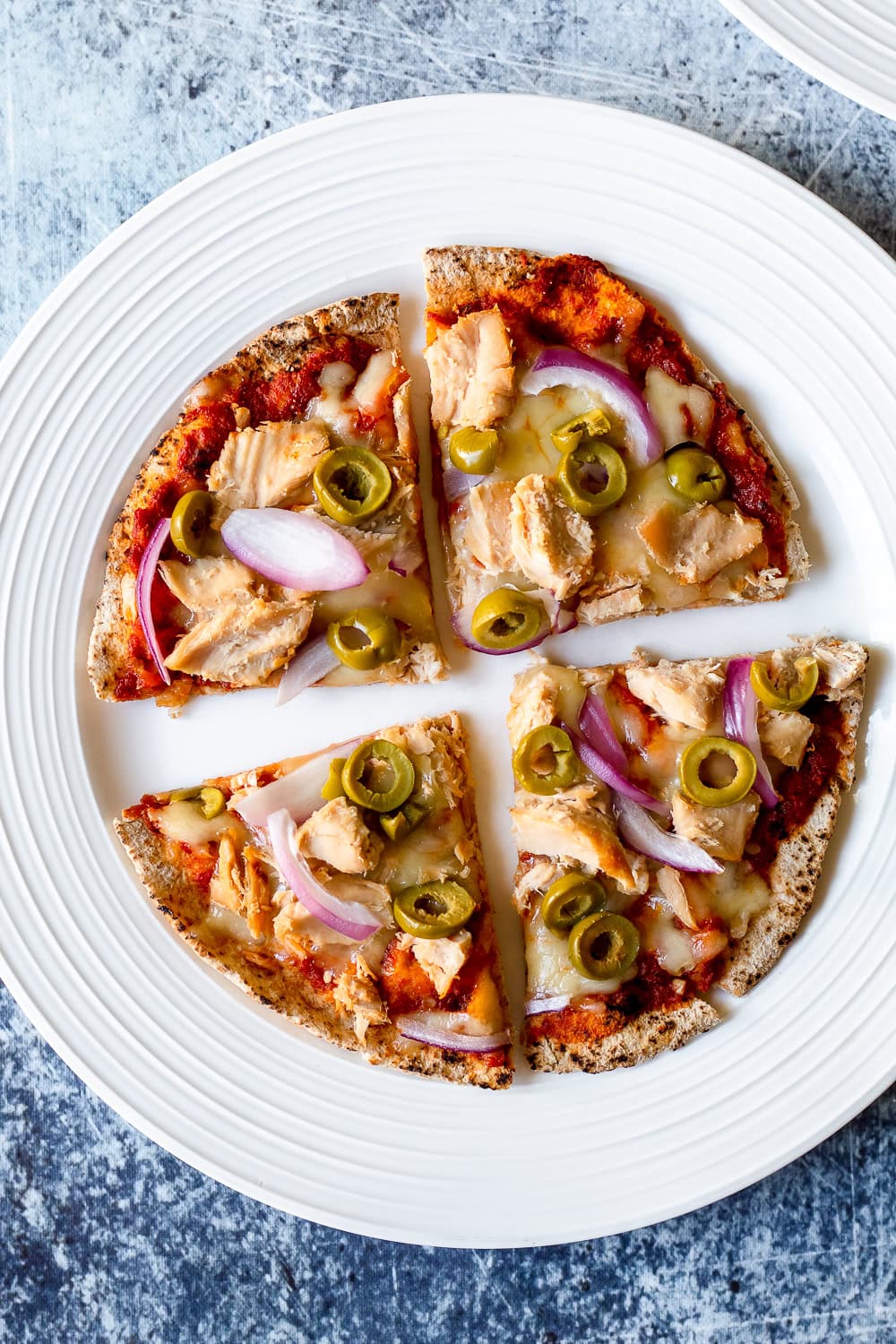 a view of the pizza on a white plate on a dark surface