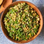 The kale, quinoa, and chickpea salad in a large wooden bowl against a dark backdrop