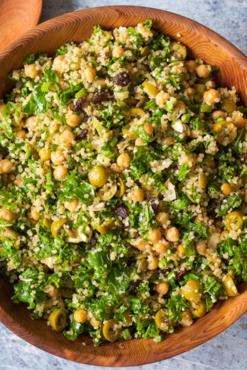 The kale, quinoa, and chickpea salad in a large wooden bowl against a dark backdrop