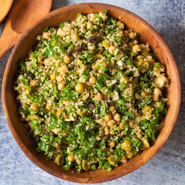 The kale, quinoa, and chickpea salad in a large wooden bowl against a dark backdrop